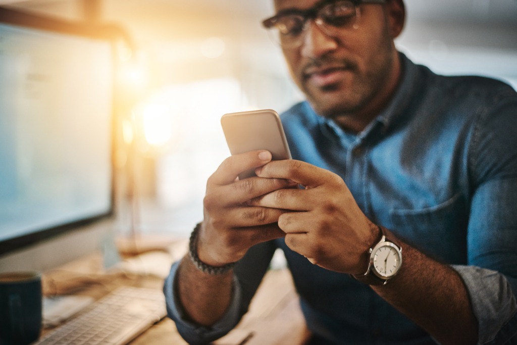 cropped-shot-of-a-young-businessman-using-a-mobile-phone-during-a-picture-id964894446